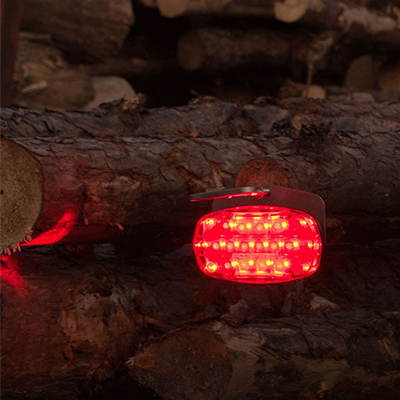 Foxfire logger lite kit - red light in use being displayed between tree logs during the night time.