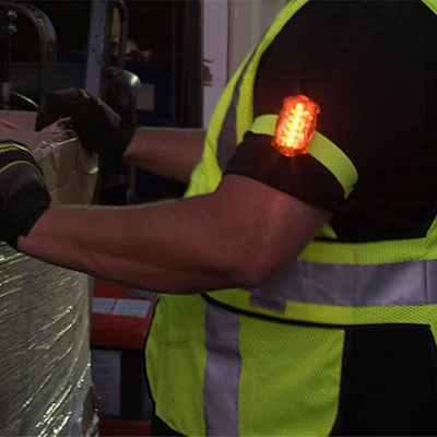 Foxfire personal led safety amber light shown in use strap on male arm.