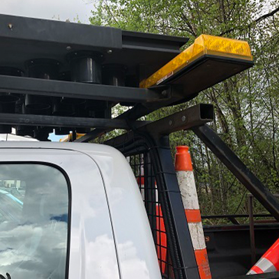 In use: Close-up side view of a 30" x 60" arrow board installed on the cab of a white truck.