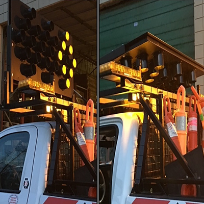 In use: side view of a 30" x 60" arrow board with amber LEDs installed on the cab of a white truck,